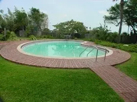 A large round swimming pool with a brick walkway around it