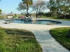 There is a large swimming pool in the middle of a lush green field.