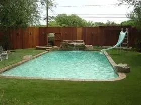 A large swimming pool with a slide in the backyard.