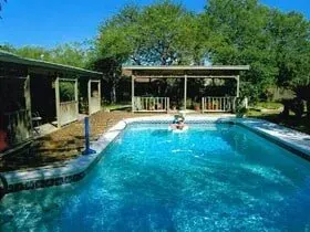 A man is swimming in a large swimming pool in front of a house.