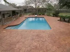 There is a large swimming pool in the backyard of a house.