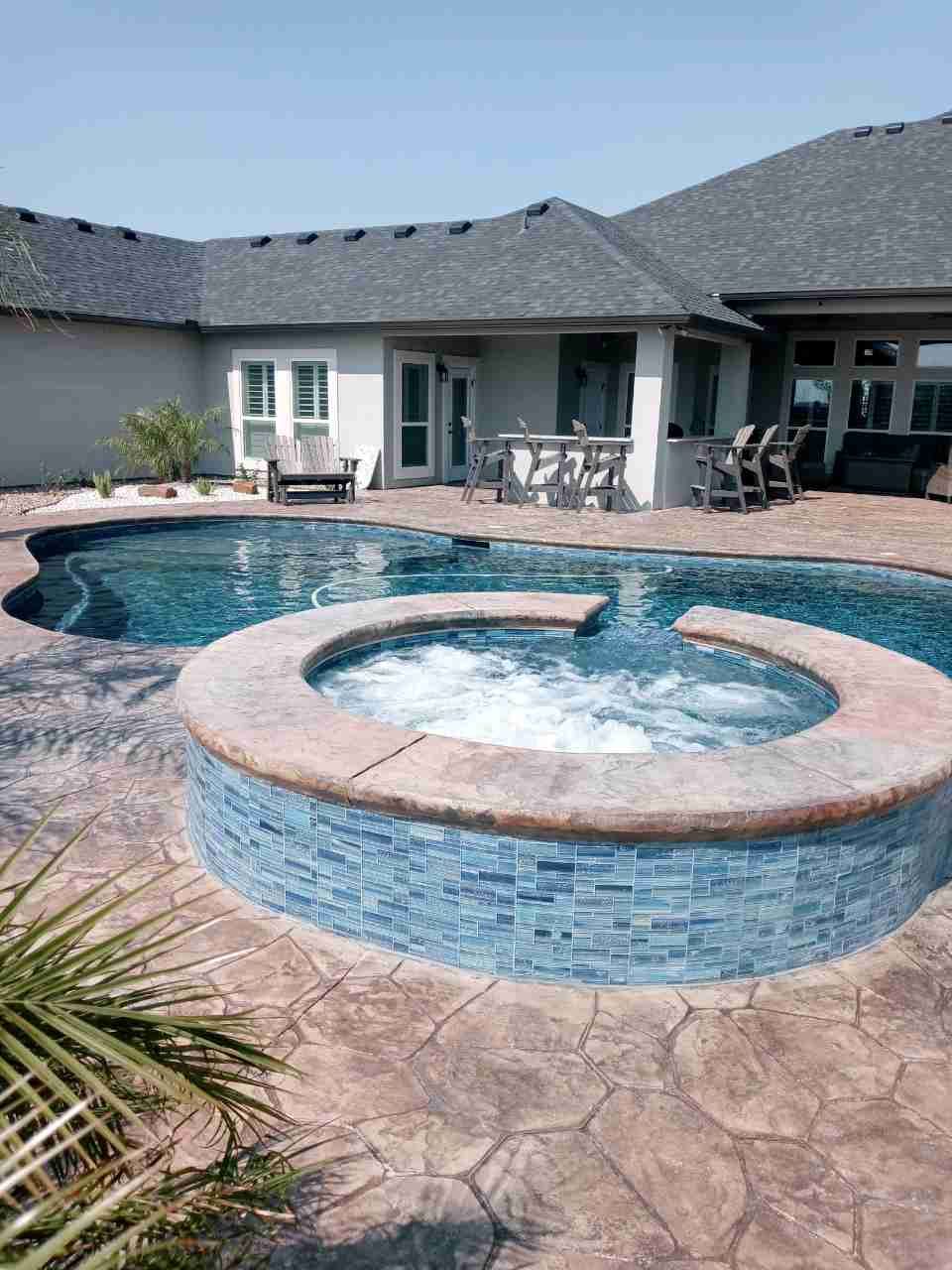 A large swimming pool with a hot tub in the middle of it.
