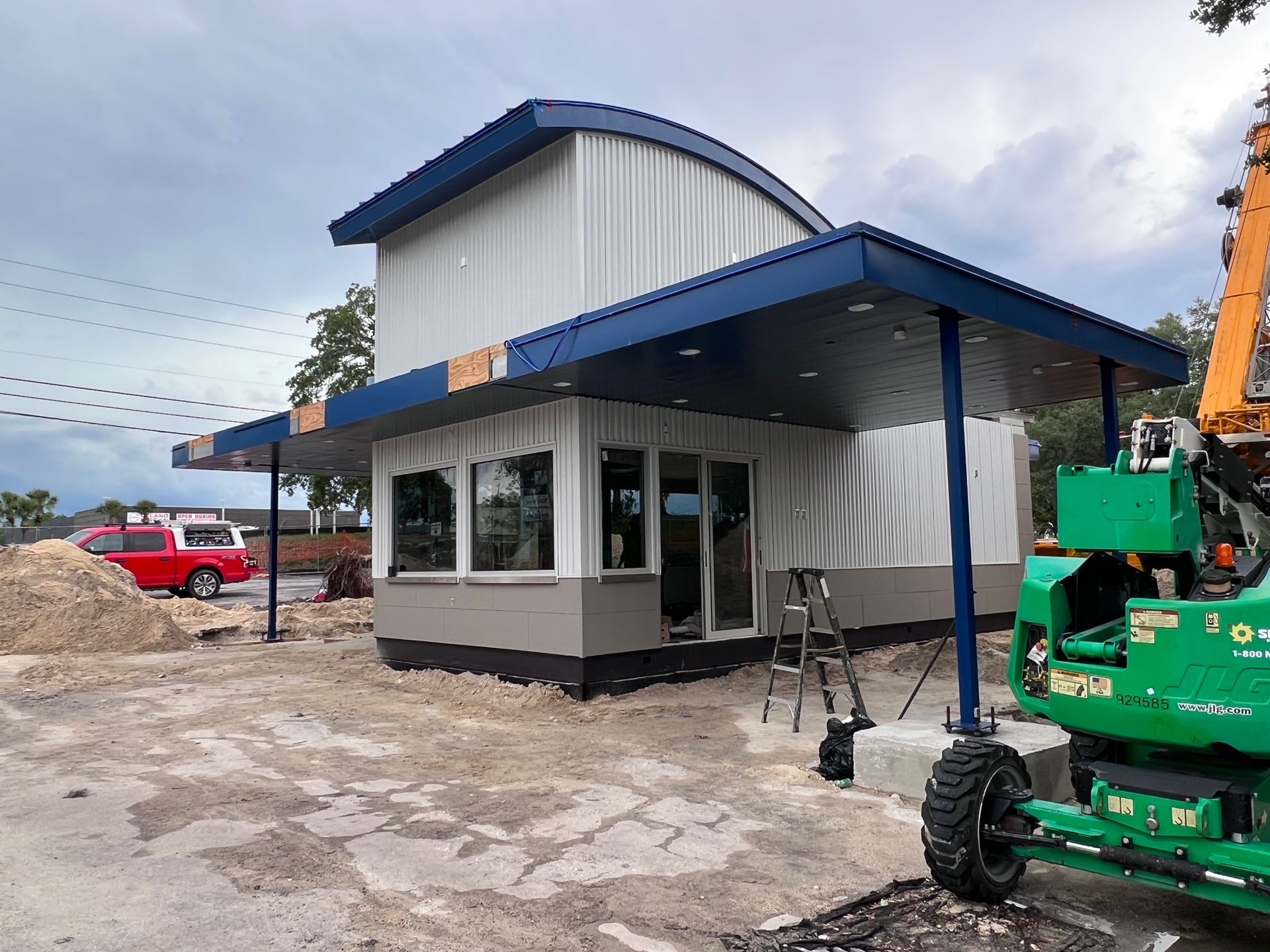 A green tractor is parked in front of a building under construction