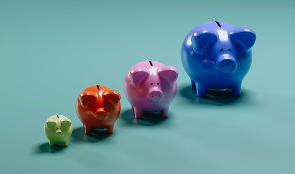 Four multicolored and multi-sized piggy banks against a teal background