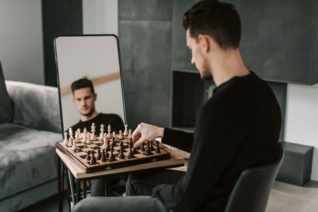 A man playing chess with himself in front of a mirror
