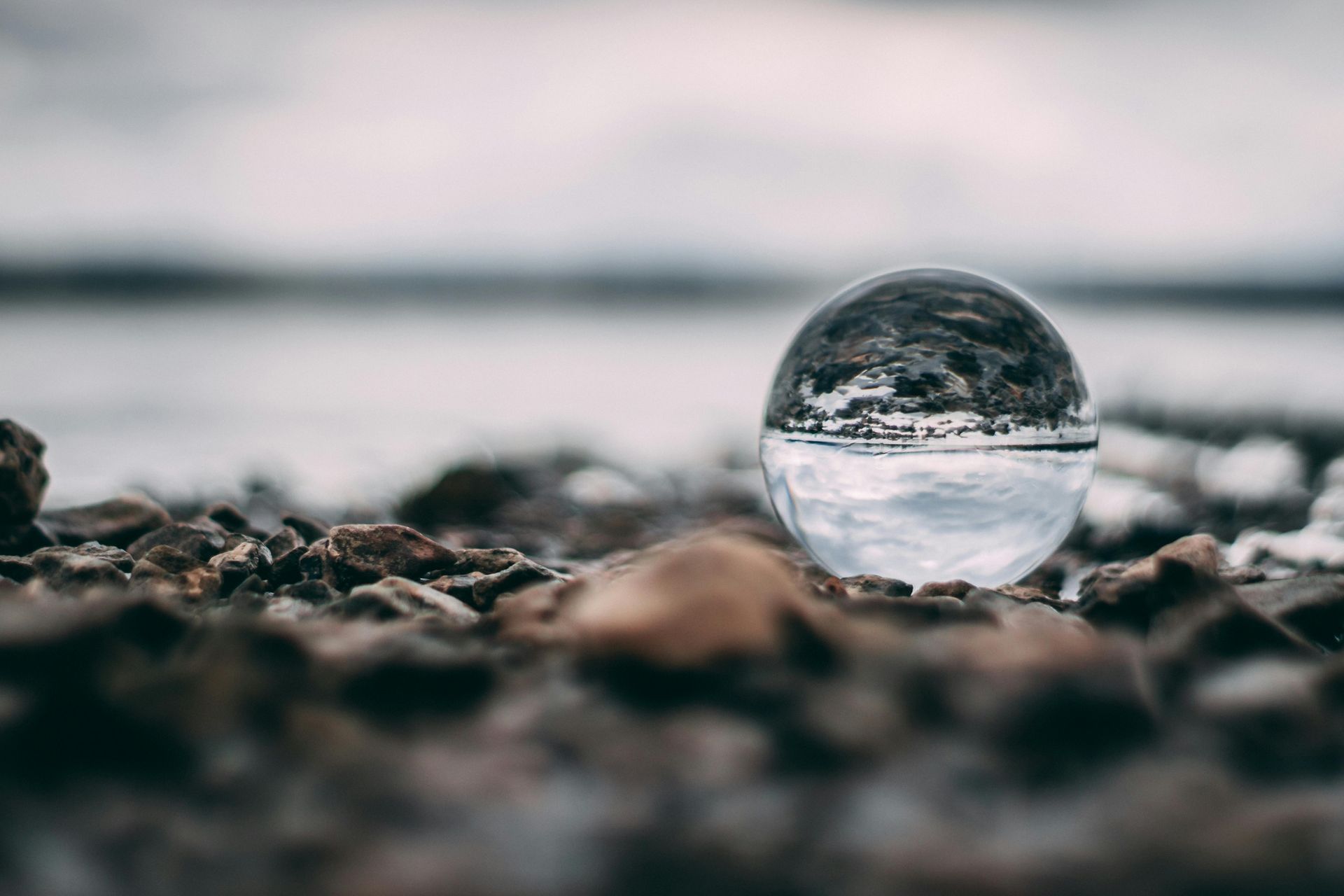 A glass ball is sitting on top of a pile of rocks with upside down reflection of the horizon