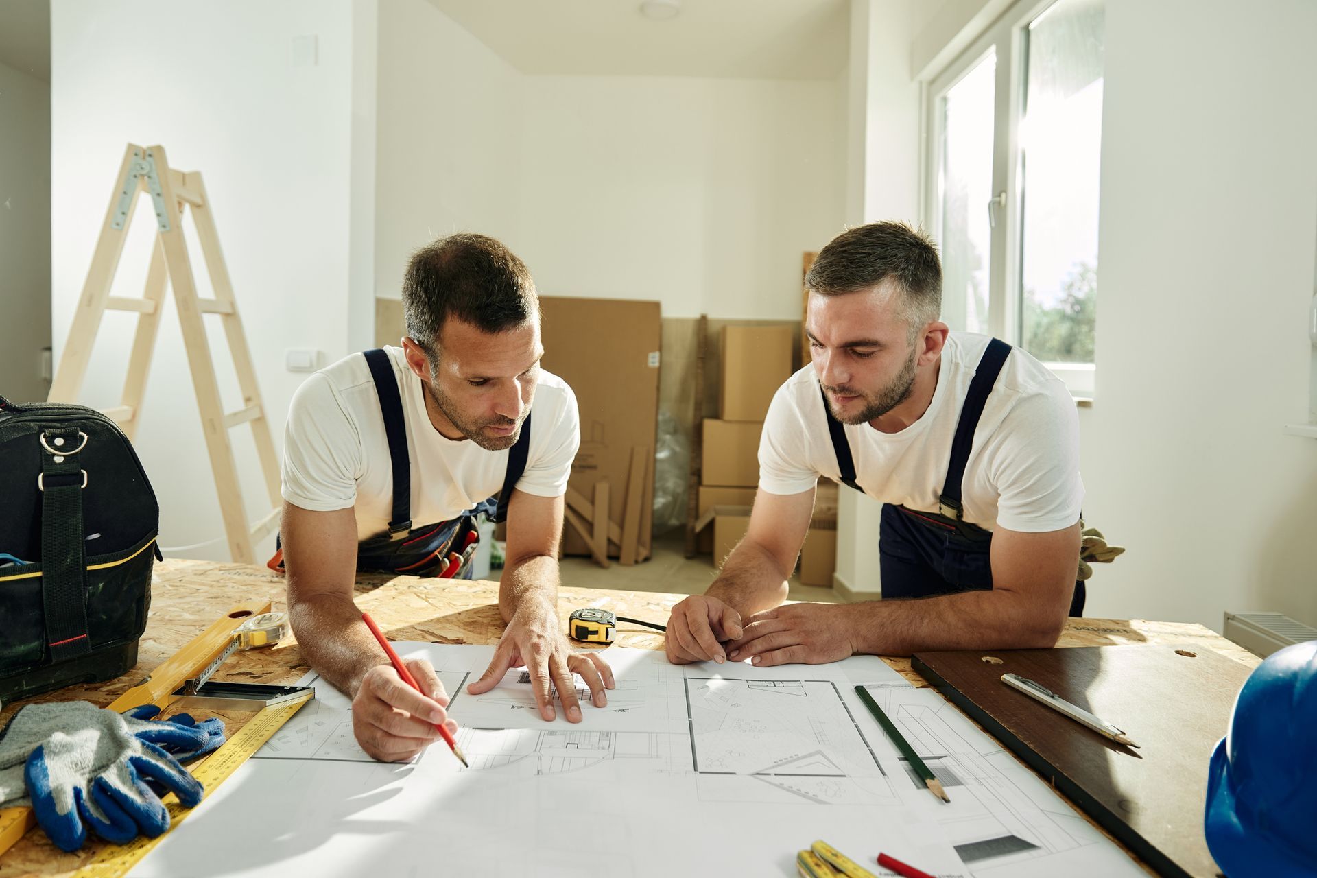 Two men are sitting at a table looking at a blueprint — Clifton, NJ — New Alp Construction