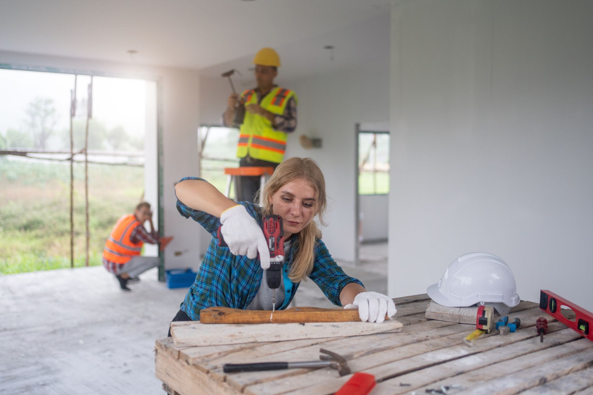 A woman is working on a wooden table with a drill — Clifton, NJ — New Alp Construction