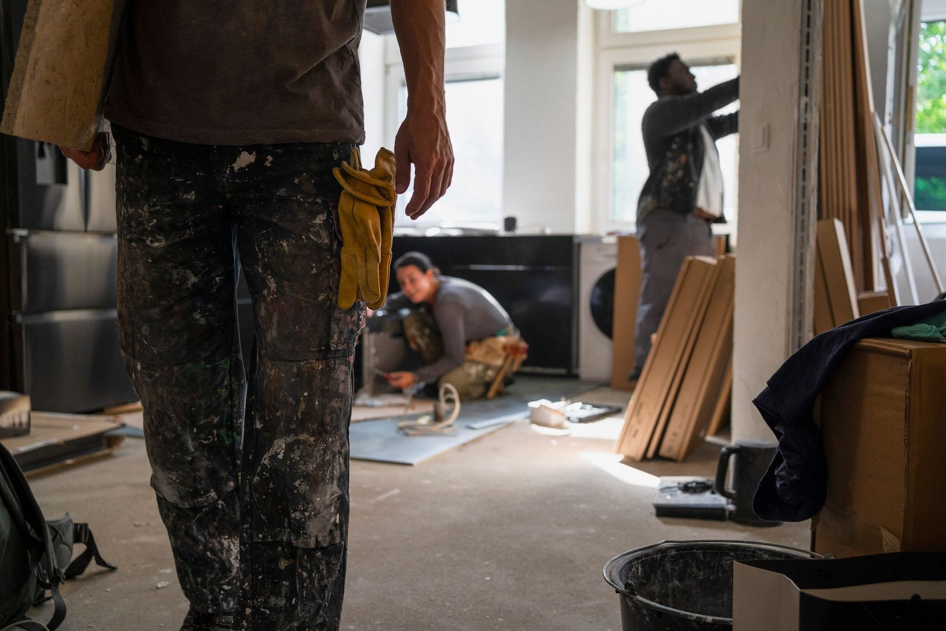 A man is standing in a room with two men working in the background — Clifton, NJ — New Alp Construction