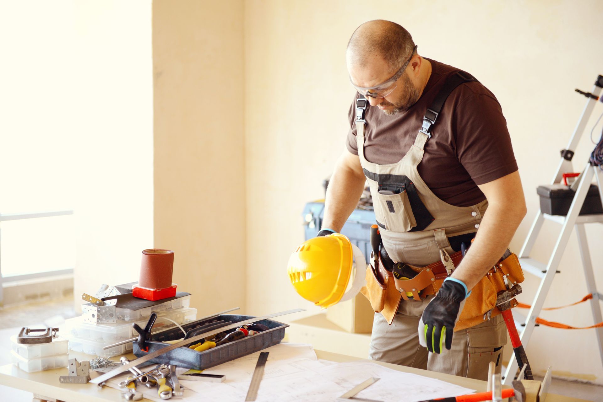 A man wearing a hard hat is standing in front of a table with tools — Clifton, NJ — New Alp Construction