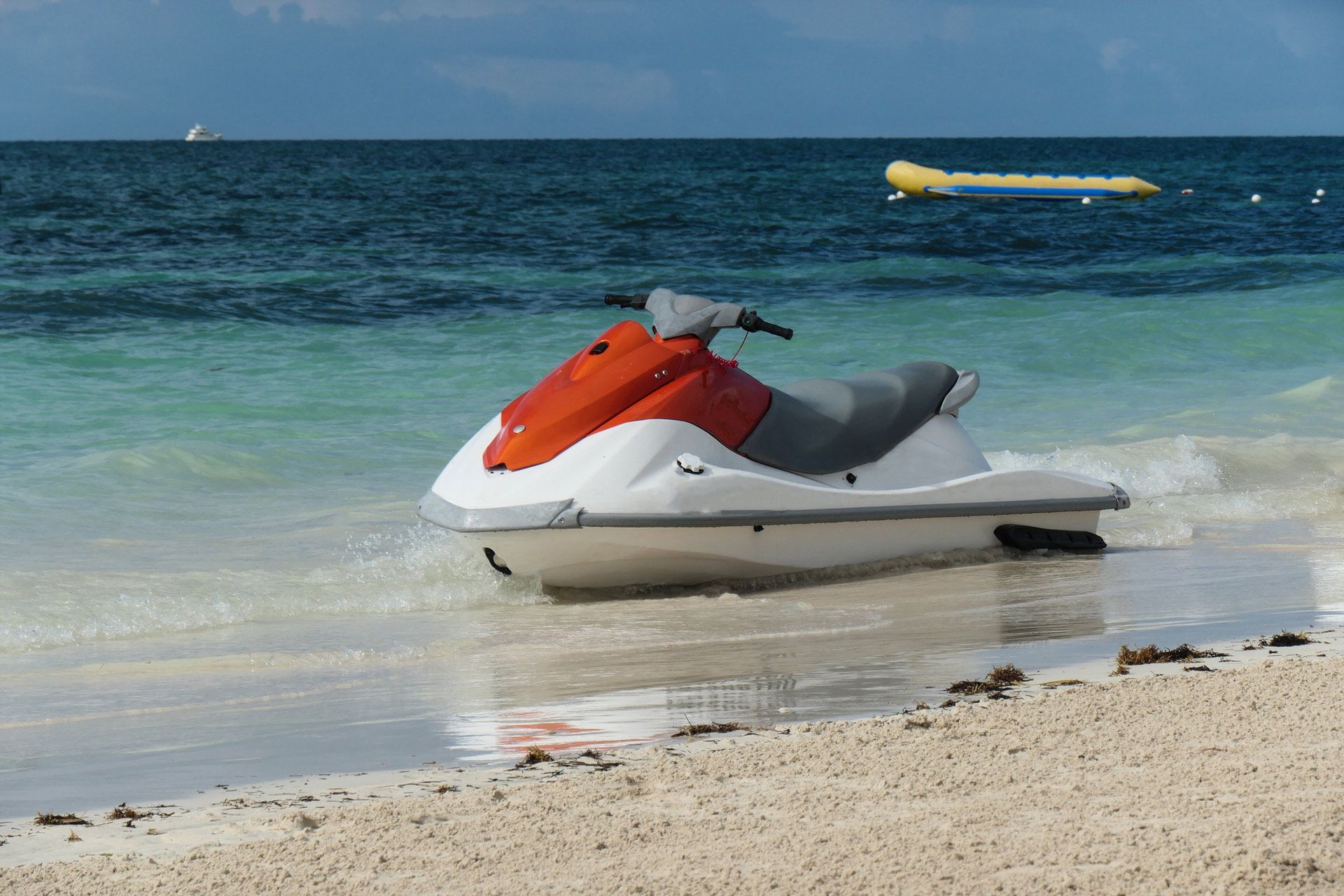 A red and white jet ski is parked on the beach