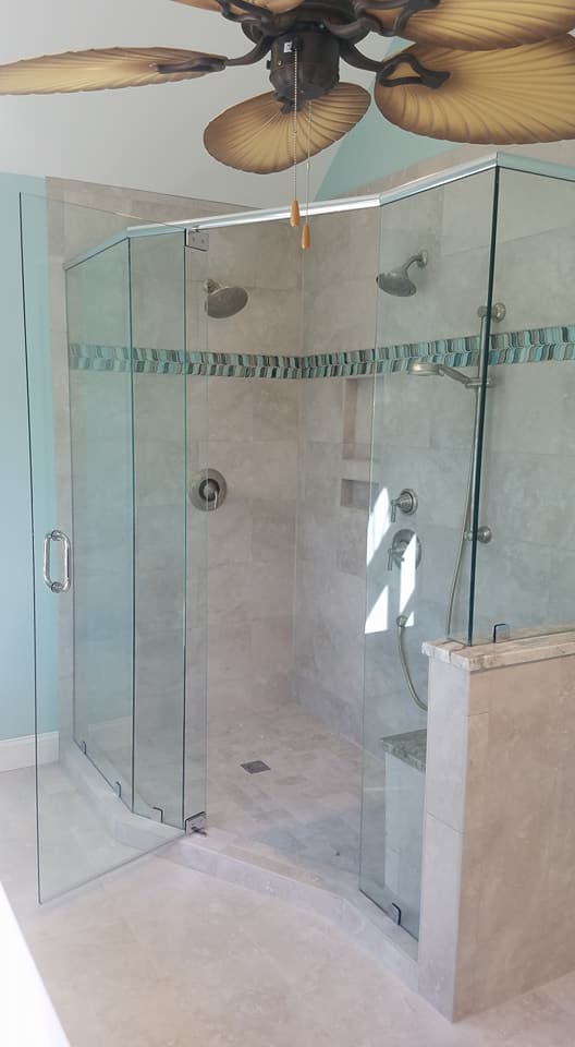 swinging glass shower door with light grey tiling on walls and floor