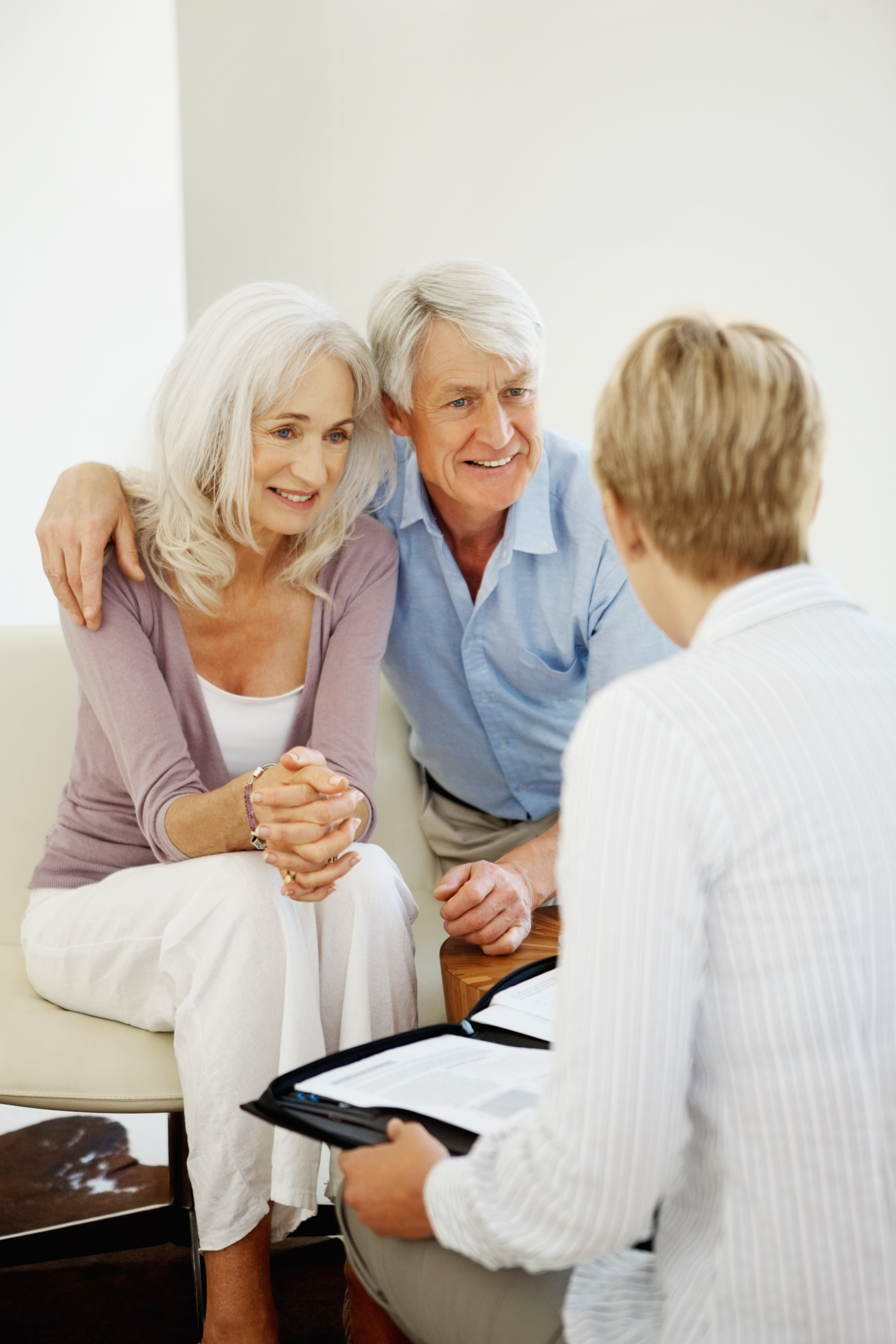 Couple smiles at each other during therapy session, seated on couch, looking at each other, indoors.