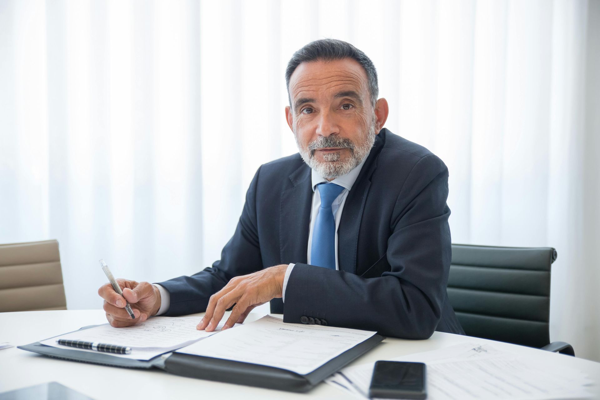 Two men in an office setting reviewing documents. One man is signing a document while the other observes.