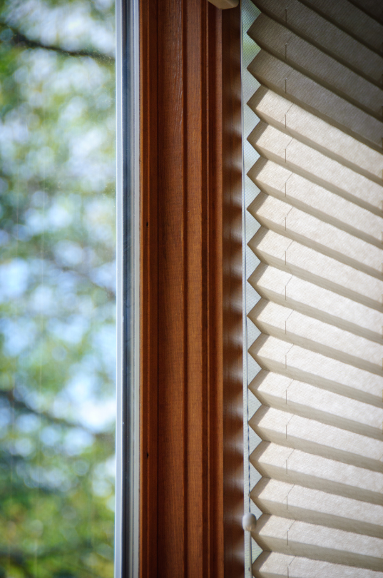 A man is installing blinds on a window in a living room.