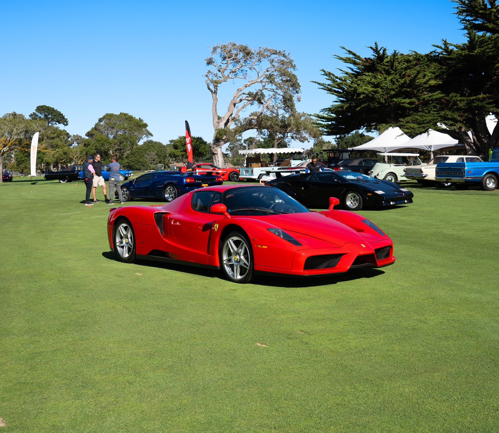 A red sports car is parked in a grassy field