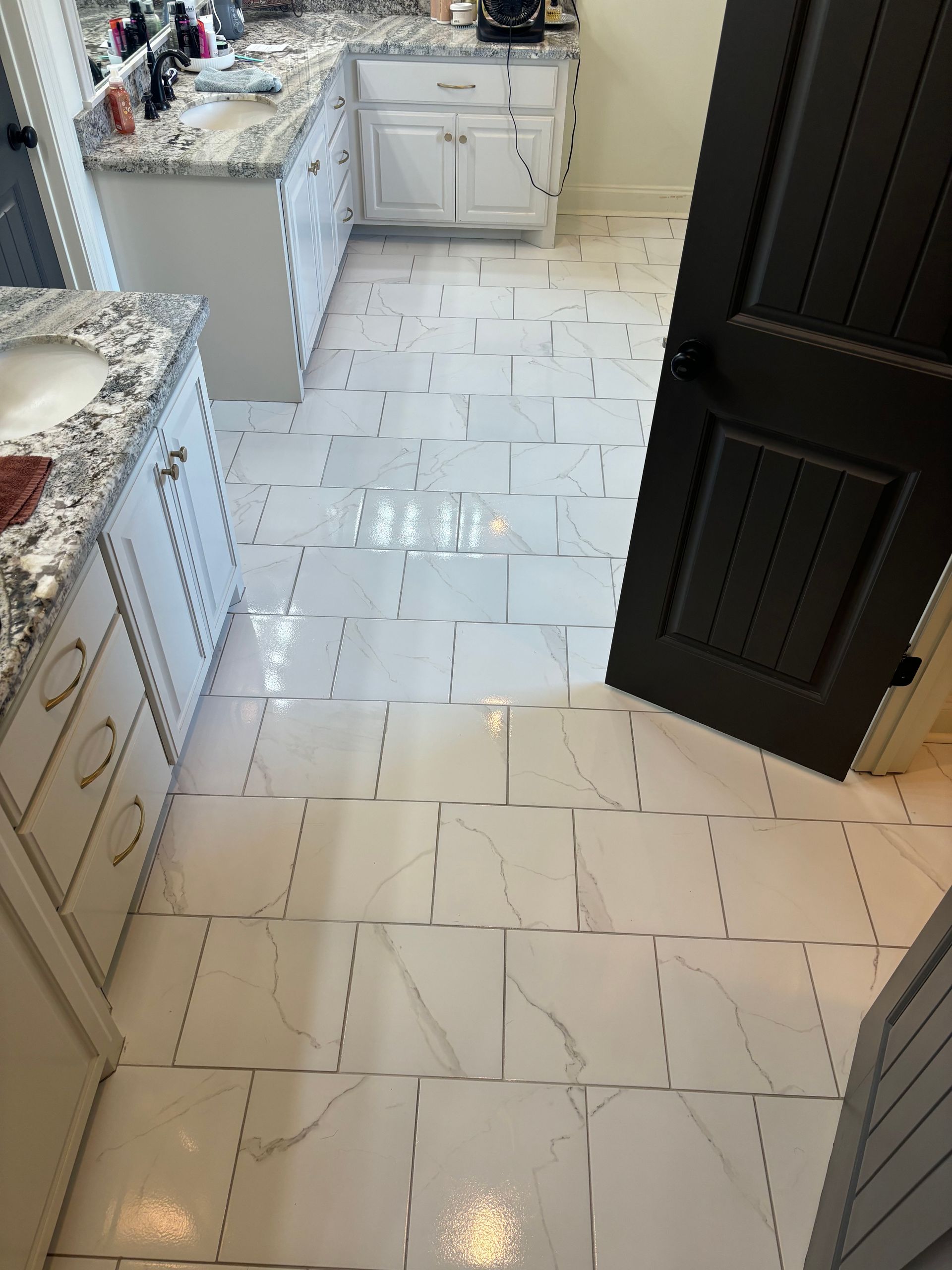 A bathroom with white tiles and a black door