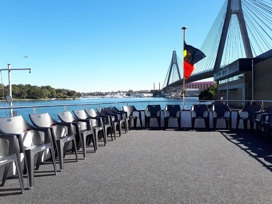 A row of chairs on a boat with a bridge in the background