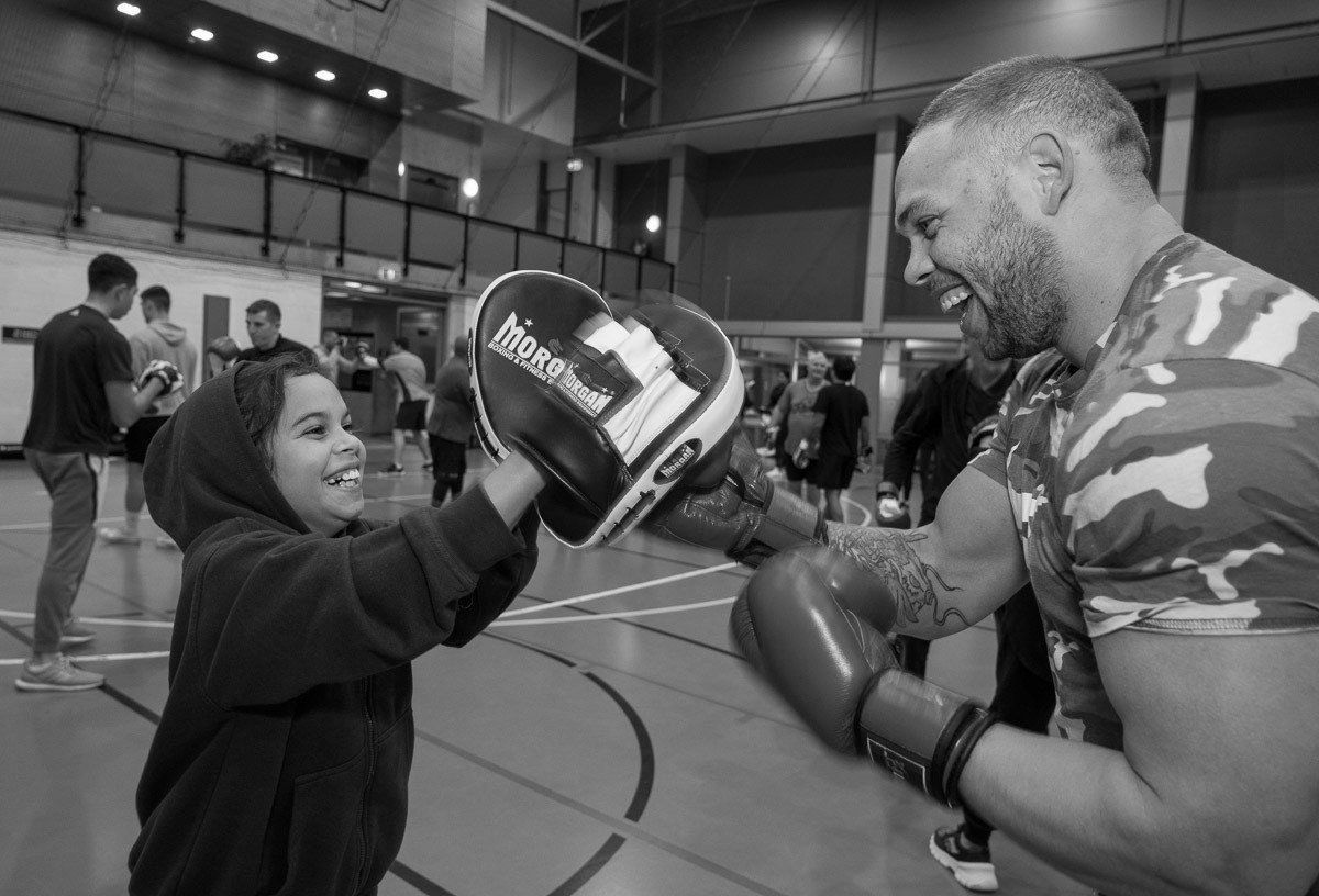 A bald man with a beard is smiling with his arms crossed.
