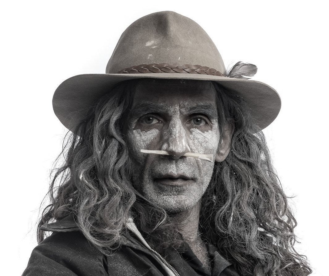 A man with long hair is wearing a cowboy hat