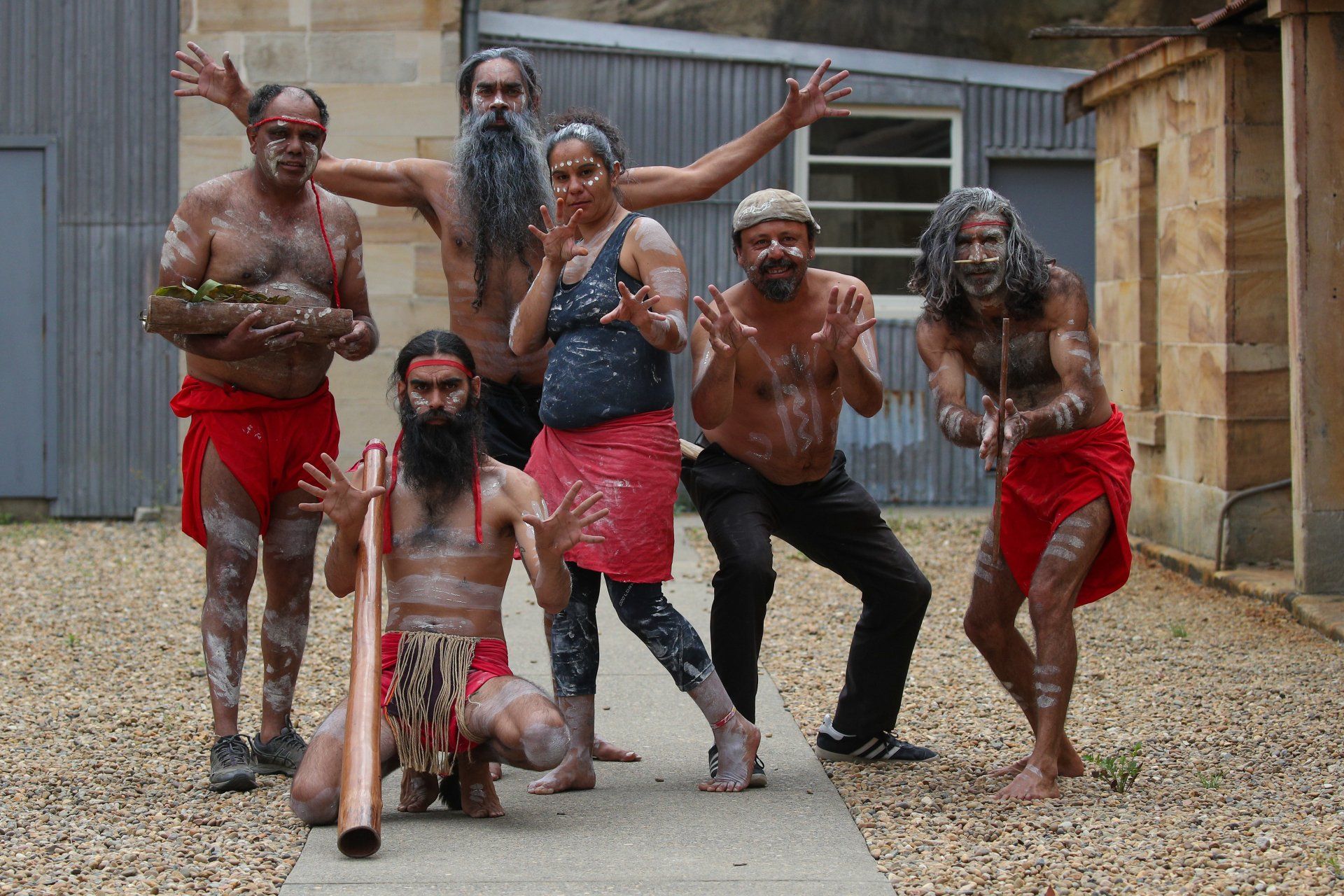 A group of people are posing for a picture and one of them is holding a didgeridoo.