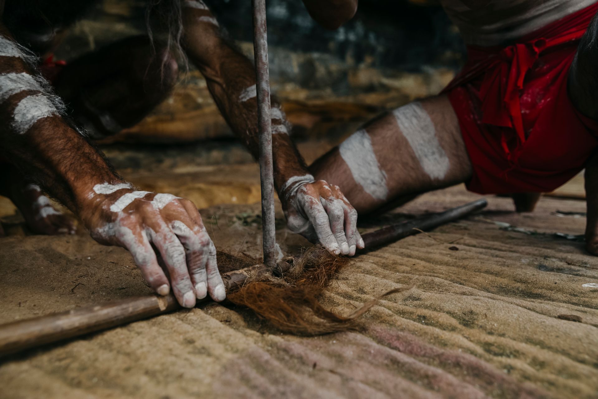A man with white paint on his hands is holding a stick.