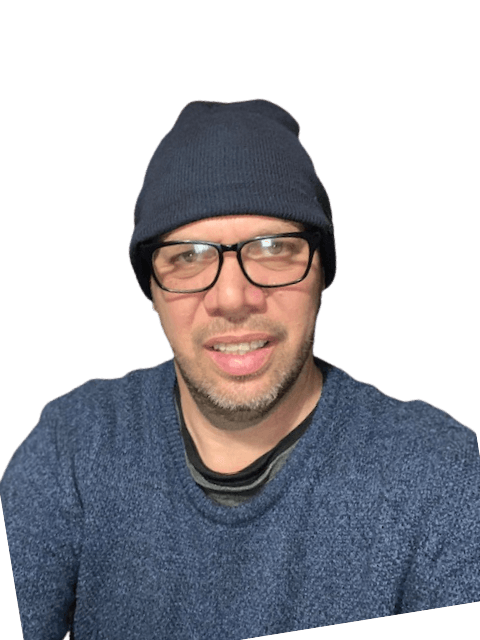 A man wearing glasses and a beanie is smiling for the camera