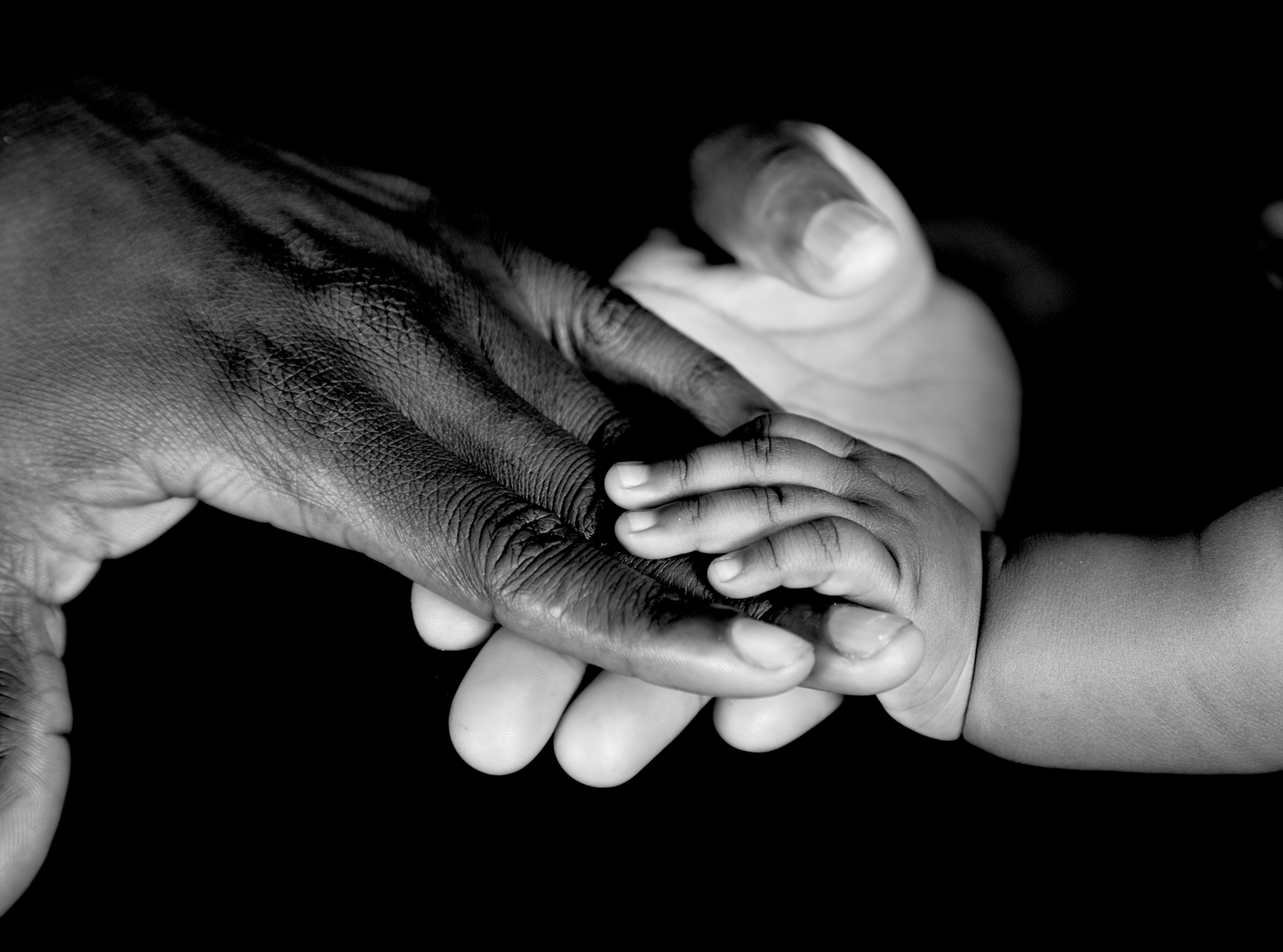 A black and white photo of a person holding a baby 's hand