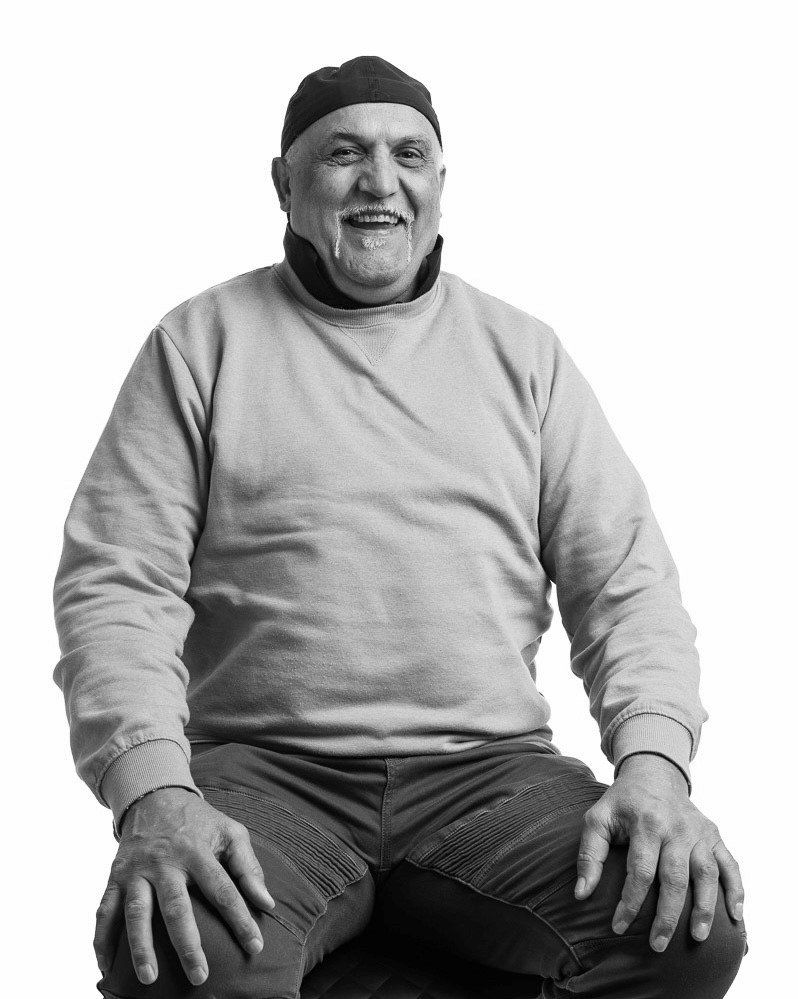 A man wearing a hat and a grey sweater is sitting down