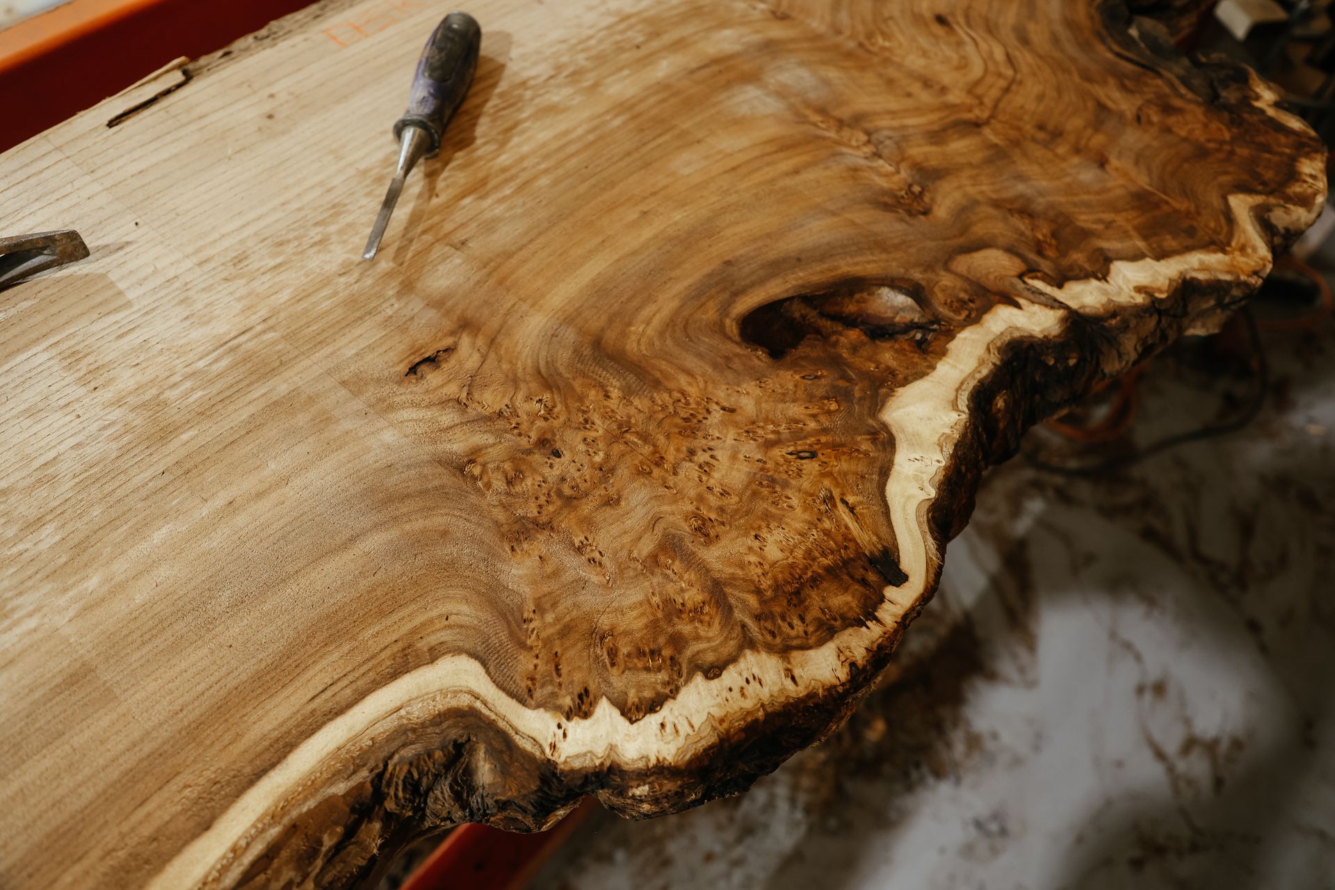 Close-up of a kiln-dried live edge wood slab with natural grain patterns, highlighting the unique ch