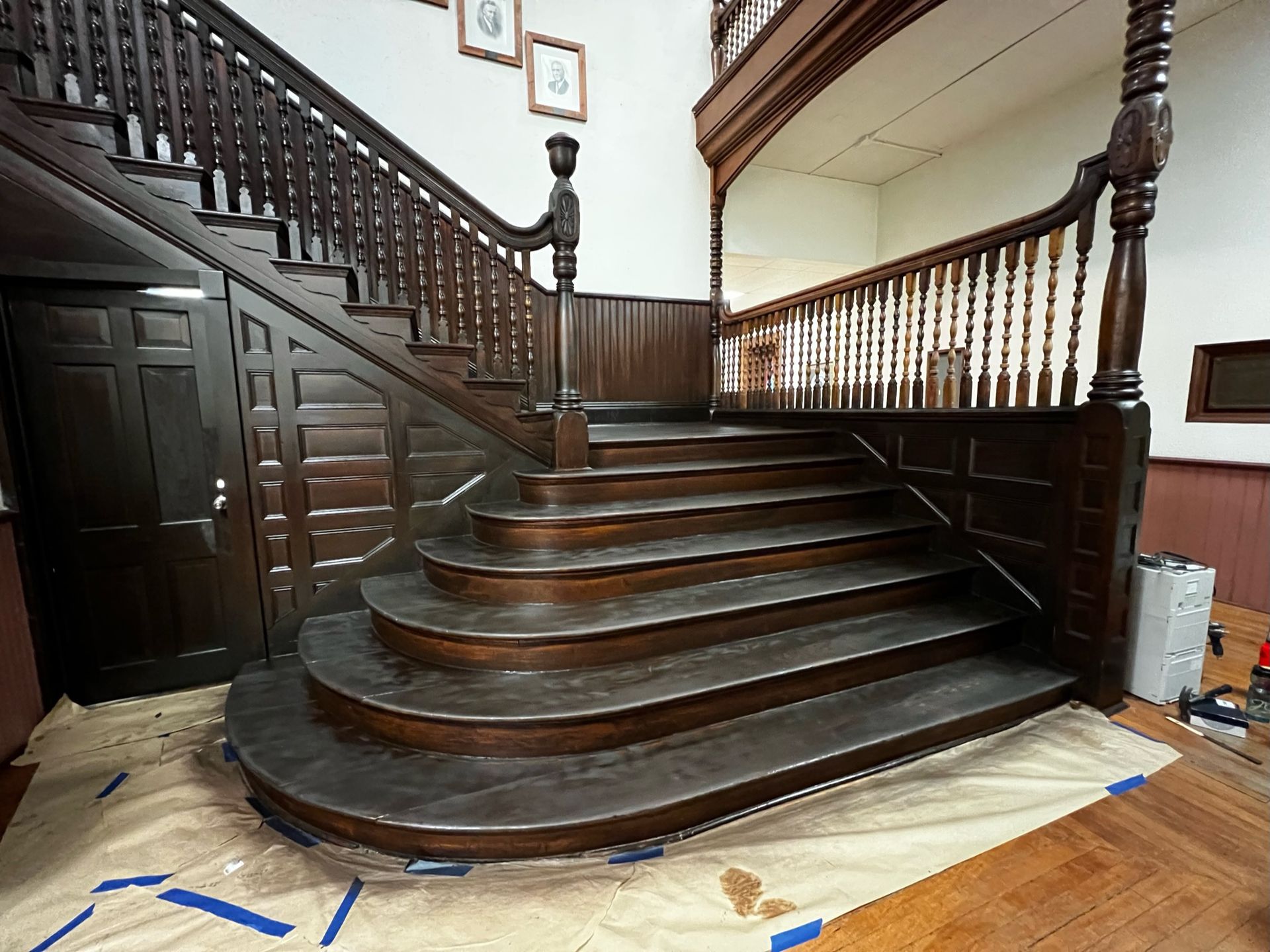 A large wooden staircase is being painted in a room