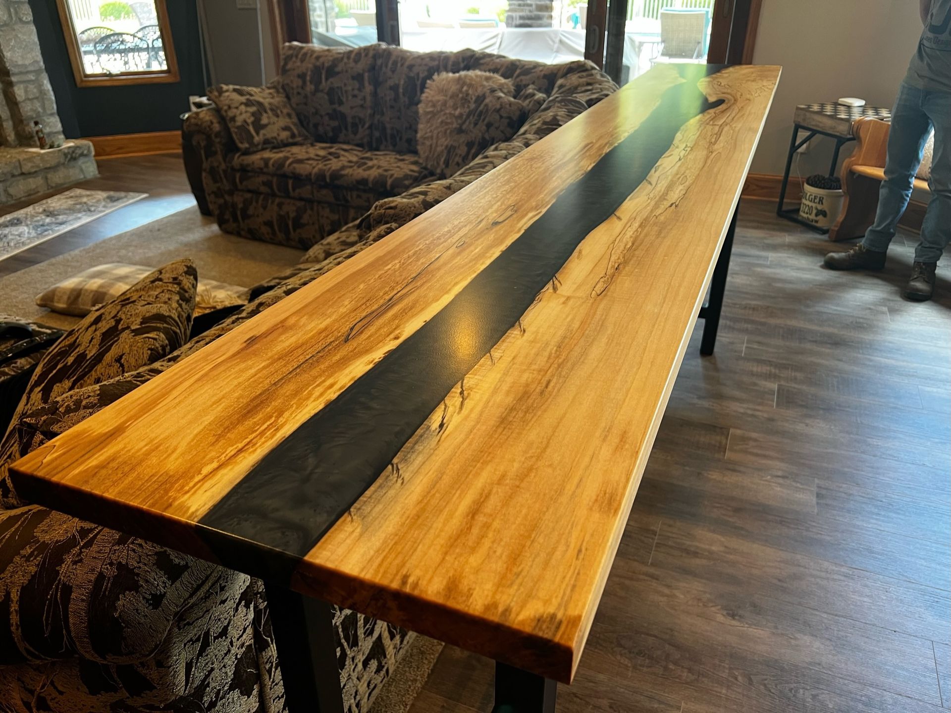 A long wooden table is sitting in a living room next to a couch.