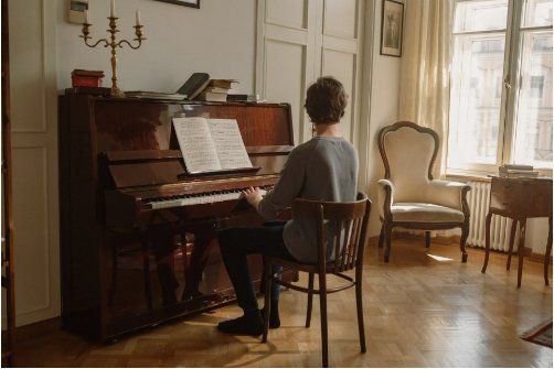 A man is sitting in a chair playing a piano in a living room.