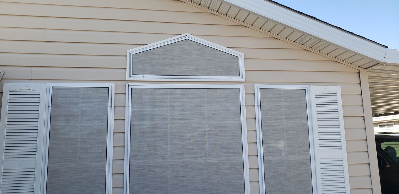 Exterior of a house with beige siding, white trim and shutters, and window coverings.