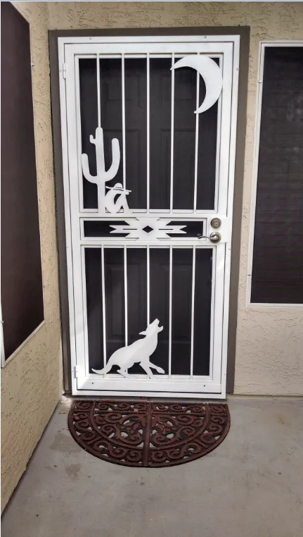 White security screen door with desert-themed cutouts, including a cactus, crescent moon, and howling wolf.