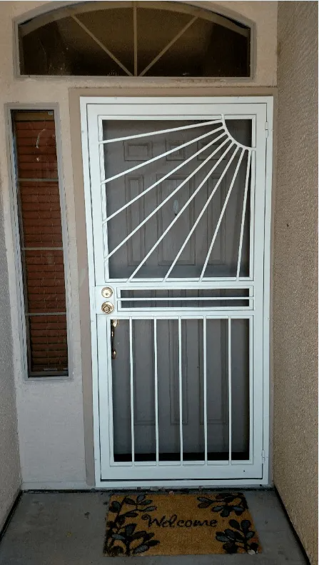 White security door with sunburst design, welcome mat, brick accent, and arched window.