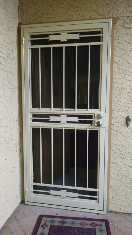 White security door with vertical bars and decorative top and bottom sections, outside an entry.