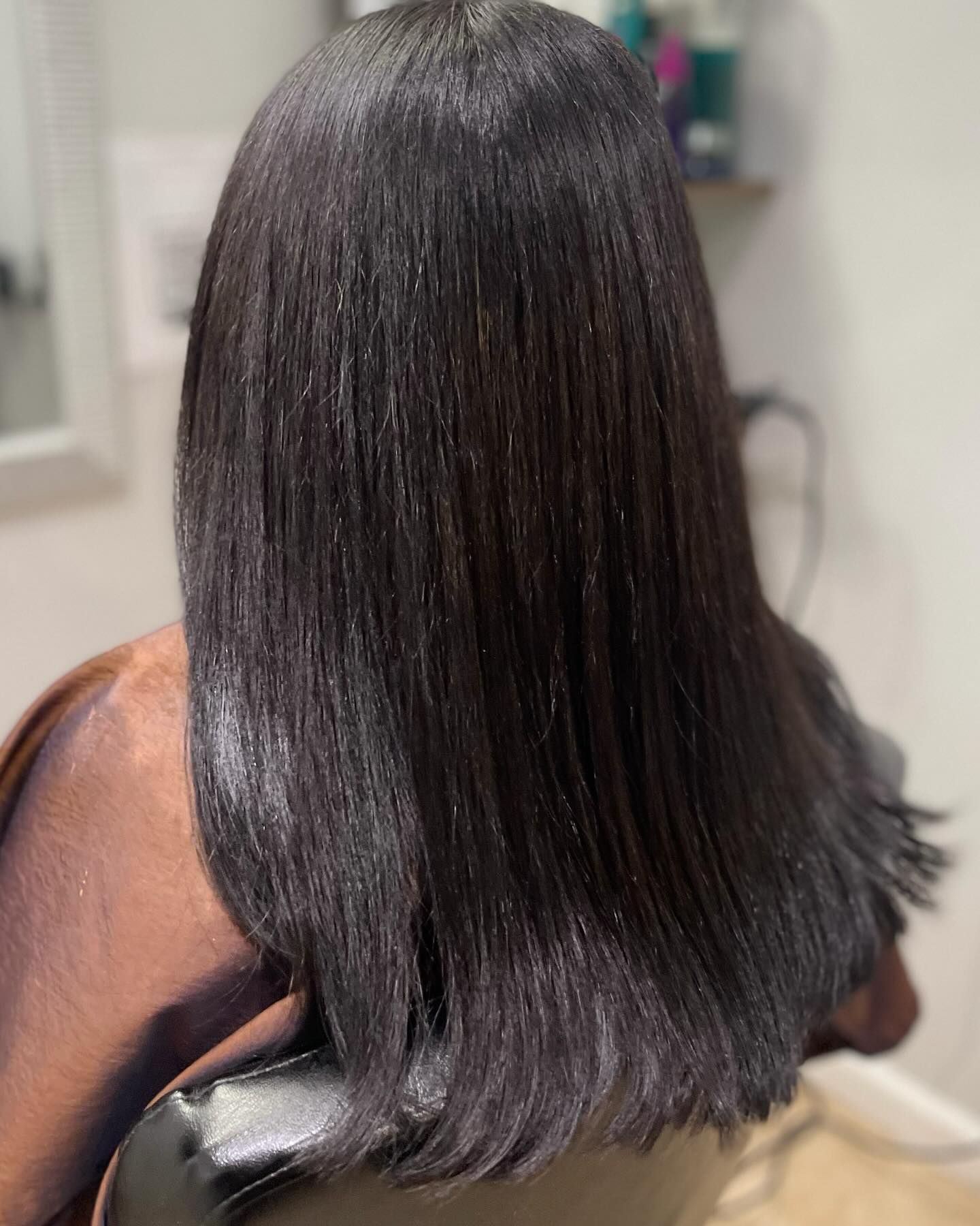 A woman with long black hair is sitting in a chair.