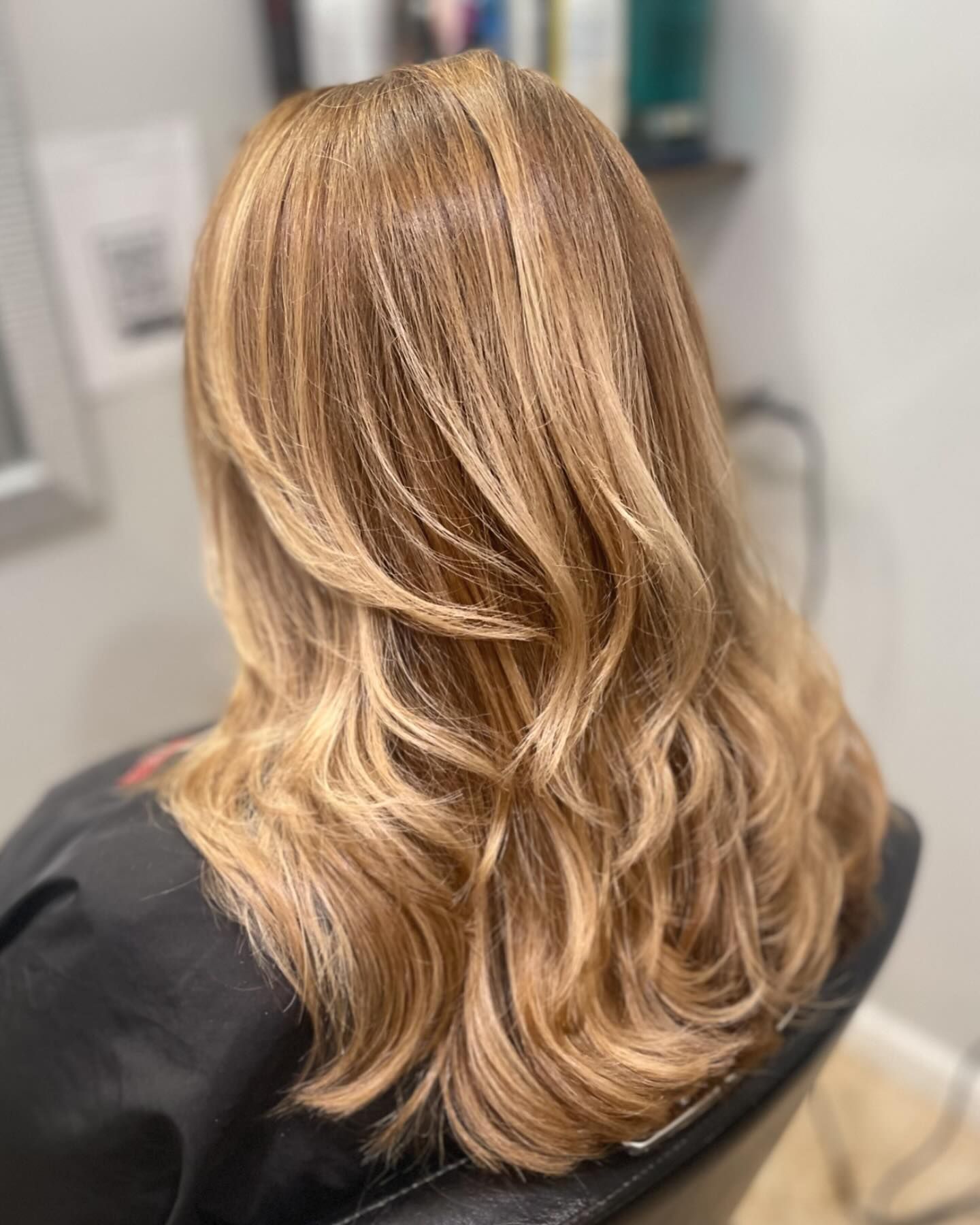 A woman with long blonde hair is sitting in a chair.