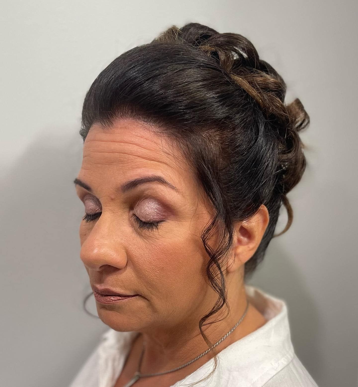 A woman with her eyes closed and her hair in a bun.