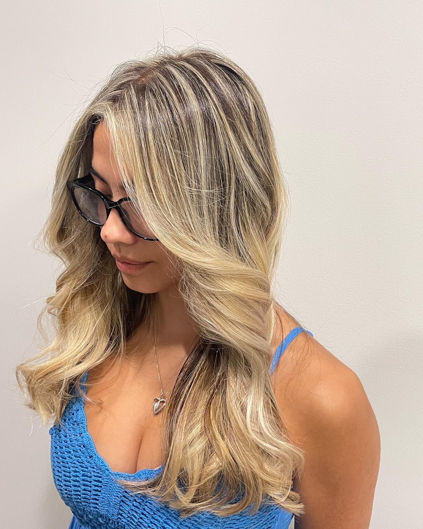 A woman with long blonde hair is wearing sunglasses and a blue top.