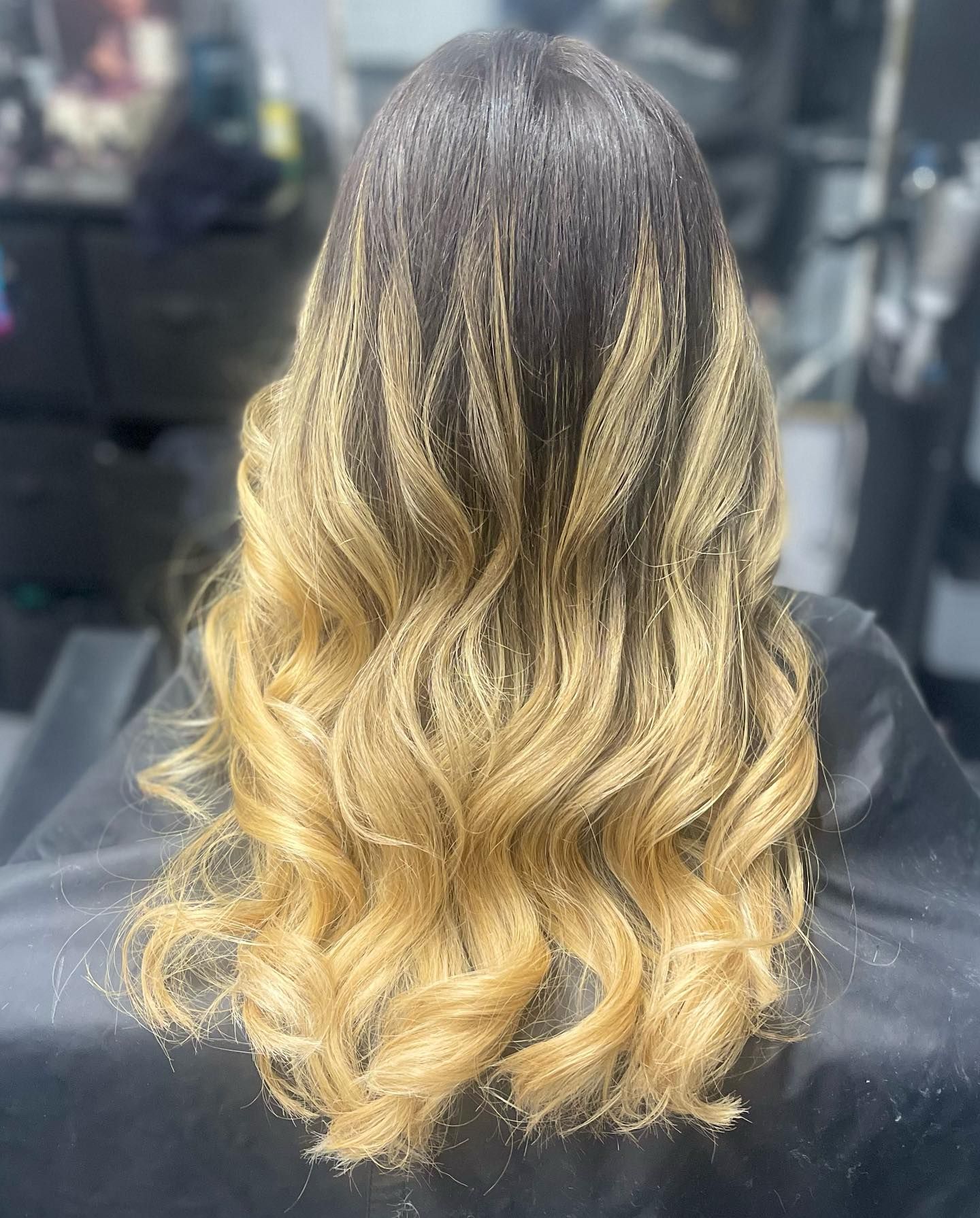 A woman with long blonde hair is sitting in a chair in a salon.