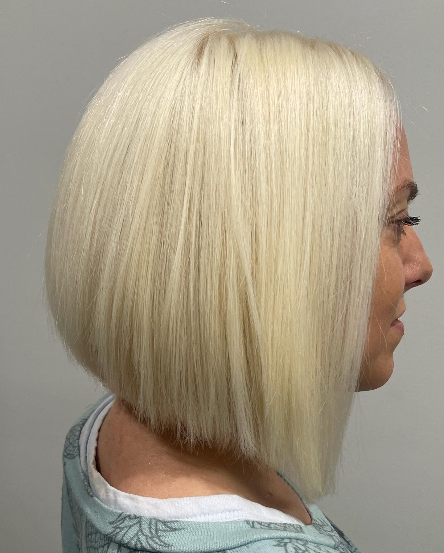 A woman with blonde hair is wearing a blue shirt and a bob hairstyle.