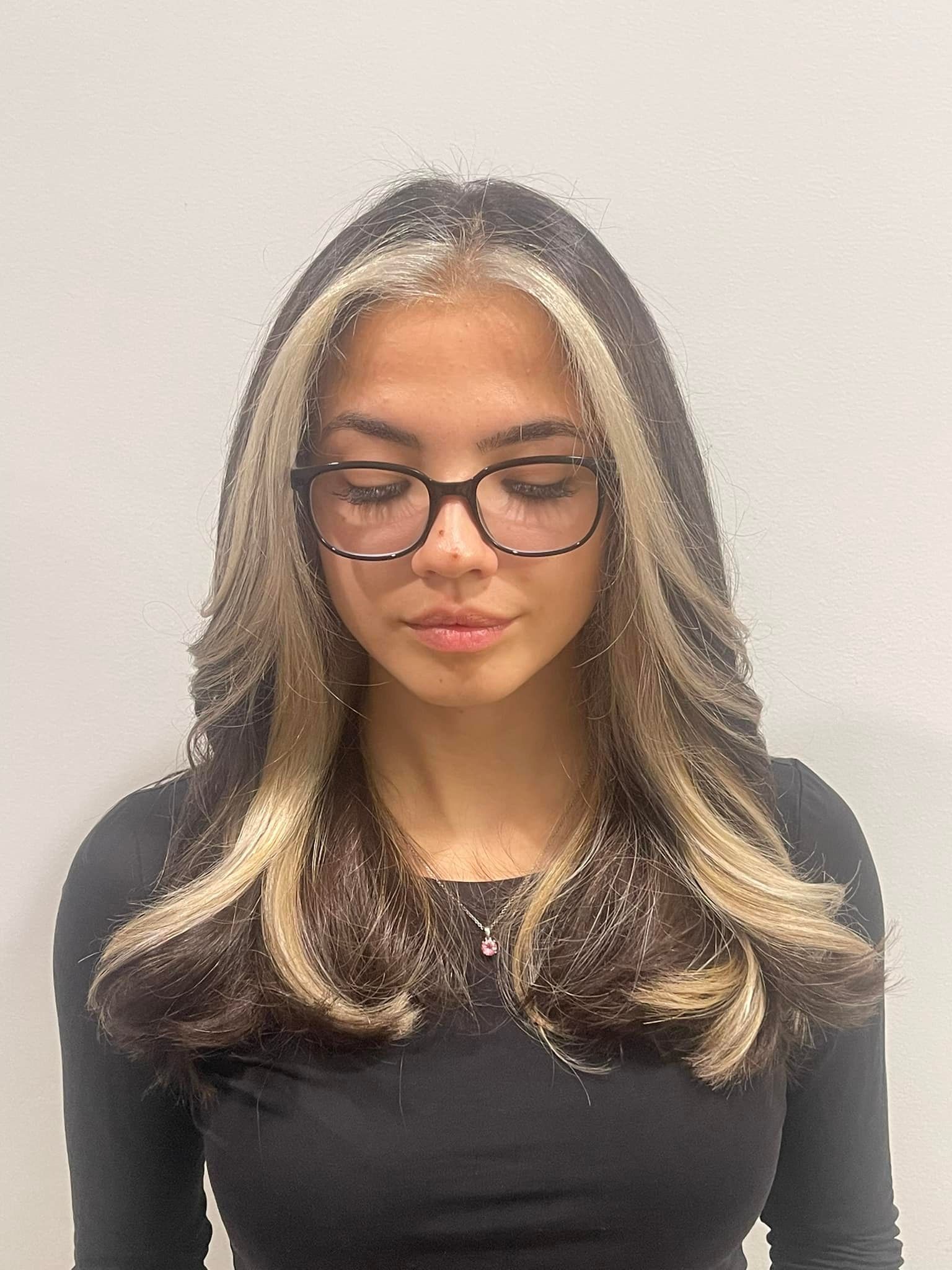 A woman with long hair and glasses is wearing a black shirt.