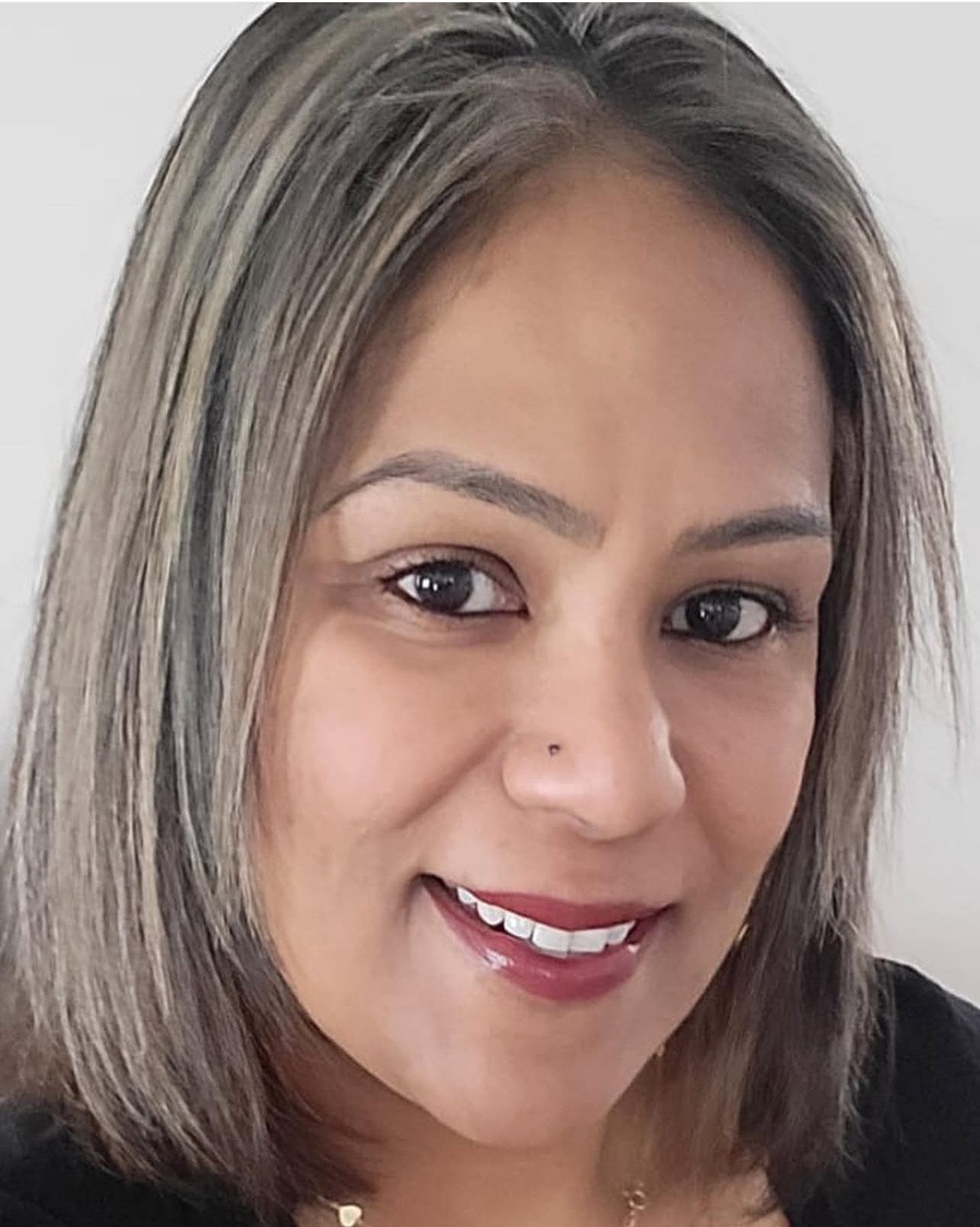 A close up of a woman 's face smiling and wearing a black shirt.