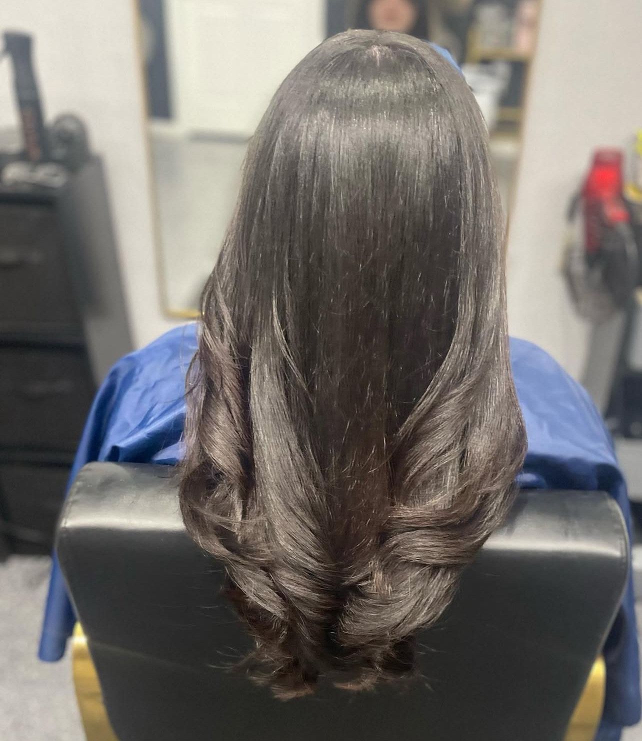 A woman is sitting in a chair with her hair in a bun.