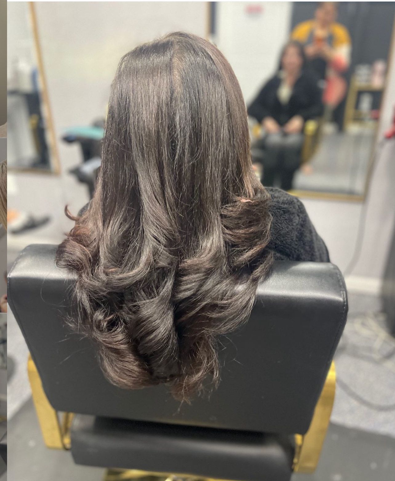 A woman with long hair is sitting in a chair in a salon.