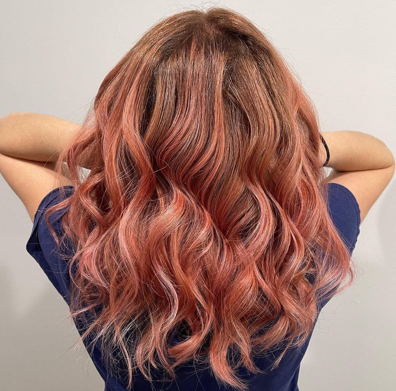 The woman is wearing a blue shirt and has pink hair.