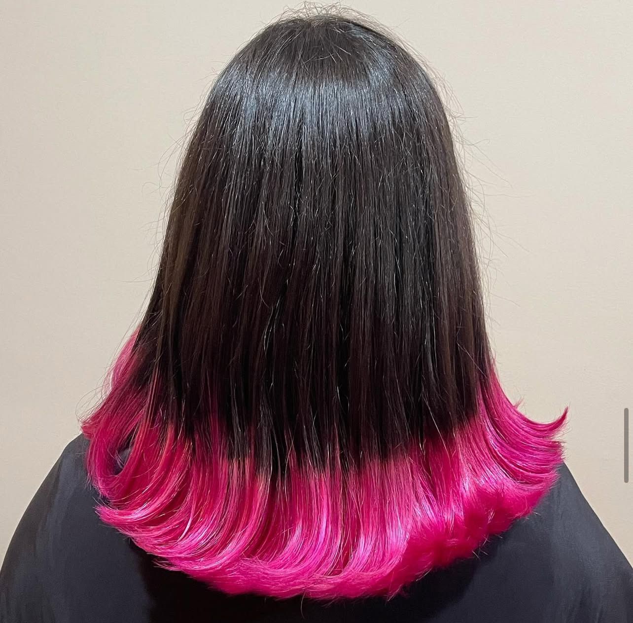 The back of a woman 's head with black hair and pink highlights.