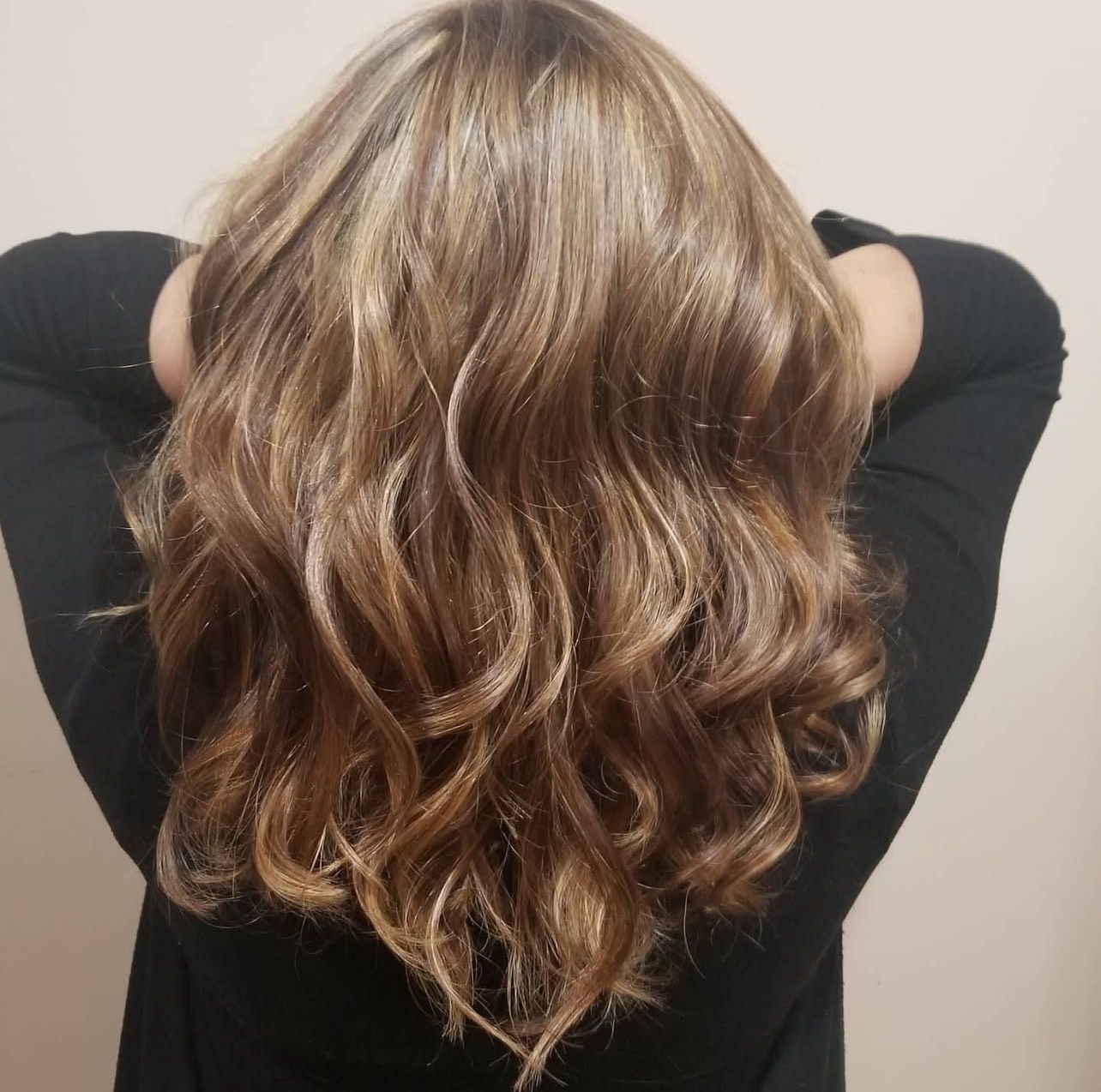 A woman in a black shirt is holding her hair up